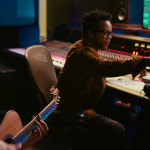 A man playing a guitar in a studio
